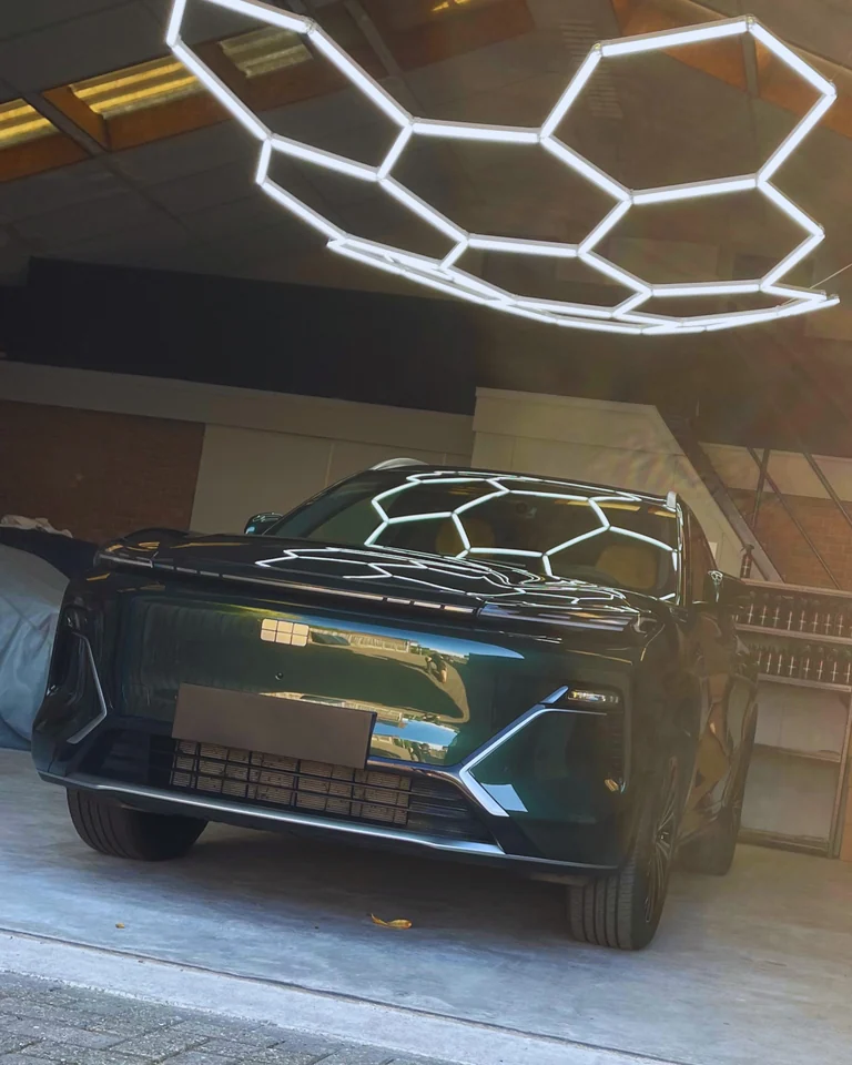 Fabrieksnieuwe auto met blanco kentekenplaat onder de hexagonverlichting in de werkplaats van DOB Detailing in Denekamp